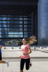 Female runner running with sportsman on footpath - IFRF01117