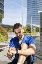 Junger Sportler, der die Zeit auf seiner Armbanduhr kontrolliert - IFRF01120