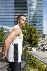 Fit sportsman with hands behind back exercising by railing - IFRF01132