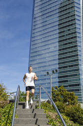 Male athlete running down on steps in city - IFRF01137