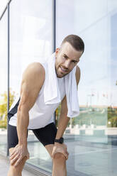 Tired young male athlete by glass wall - IFRF01145