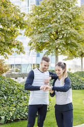 Male and female athletes checking time at park - IFRF01159