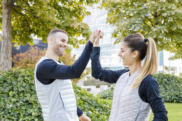 Männliche und weibliche Sportler, die sich im Park abklatschen - IFRF01161