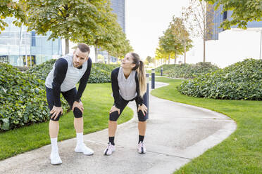 Tired man and woman standing on footpath at park - IFRF01165