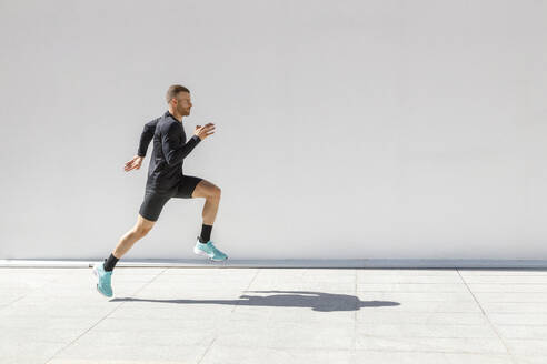 Sportler beim Laufen auf dem Fußweg an einem sonnigen Tag - IFRF01179