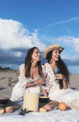 Happy female friends having drink on sunny day - RFTF00114