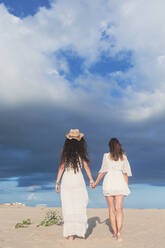 Teenage girl with mature woman walking on beach - RFTF00131