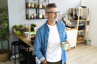 Man with hand in pocket holding coffee cup at home - GIOF13893