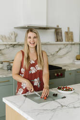 Happy female professional cutting strawberry in kitchen - SMSF00563