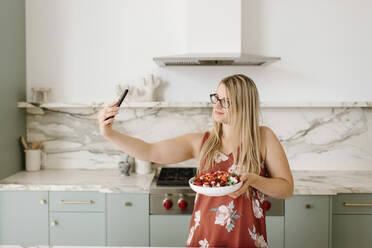 Ernährungsberaterin mit Lebensmitteln, die ein Selfie mit ihrem Smartphone in der Küche machen - SMSF00584