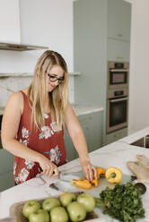 Female dietician cutting vegetable in kitchen - SMSF00585