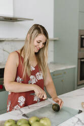 Female nutrient expert chopping food on cutting board in kitchen - SMSF00588