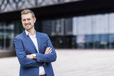 Smiling male professional standing with arms crossed - WPEF05379