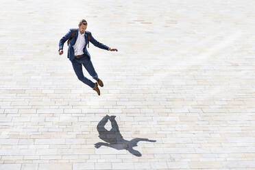 Young businessman jumping on footpath - WPEF05394