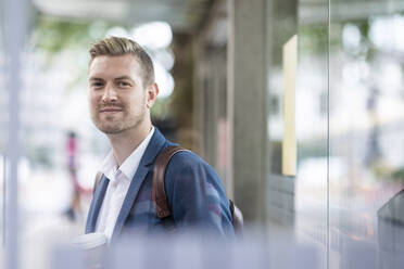 Smiling male professional standing at bus stop - WPEF05426