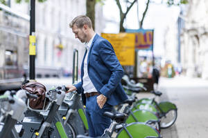 Businessman with hand in pocket standing at bicycle parking station - WPEF05431