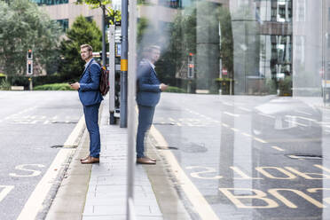 Young businessman with backpack waiting at bus stop - WPEF05438