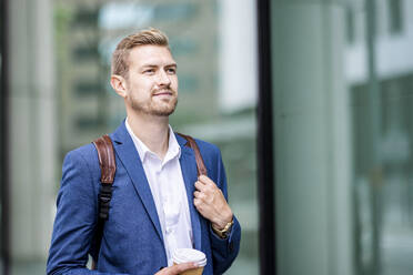 Male professional with backpack holding disposable cup - WPEF05443