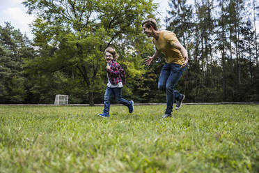 Happy son playing with father on grass - UUF24866