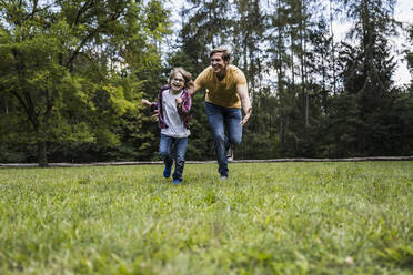 Verspielter Sohn und Vater laufen im Park auf dem Rasen - UUF24867