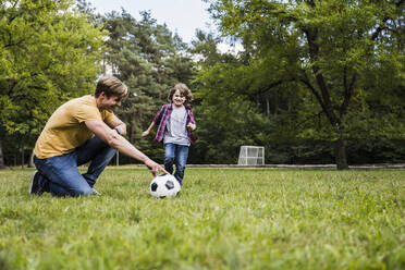 Family playing with soccer ball on grass - UUF24873