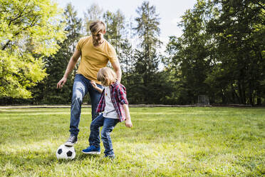 Father and son playing with soccer ball at park - UUF24875