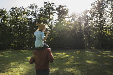 Father carrying son on shoulders at park - UUF24906