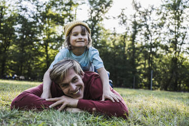 Vater und Sohn liegen im Gras im Park - UUF24911