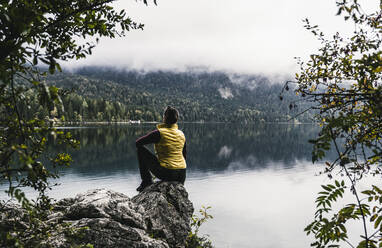 Frau sitzt auf einem Felsen am See im Wald - UUF24915