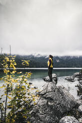 Woman standing on rock by lake - UUF24927