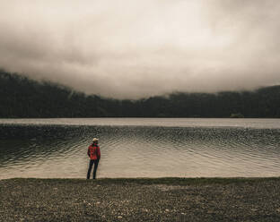 Mature man standing at lakeshore - UUF24931