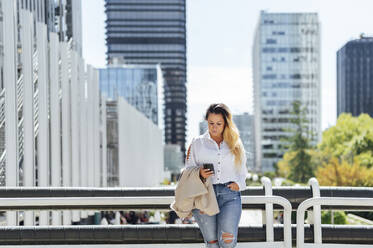 Geschäftsfrau mit Mobiltelefon in der Stadt - PGF00835