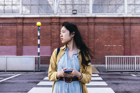 Frau mit Mobiltelefon beim Überqueren der Straße - ASGF01652