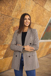 Smiling businesswoman with arms crossed by wall - ACPF01377