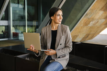 Smiling businesswoman with laptop on bench - ACPF01382