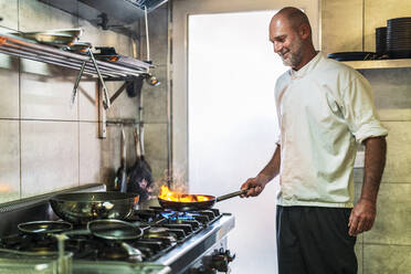 Smiling male chef cooking in restaurant - DLTSF02304