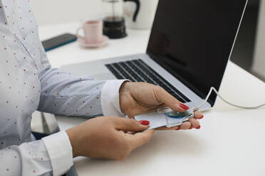 Female freelancer scanning credit card through reader while working at home office - MOMF00939