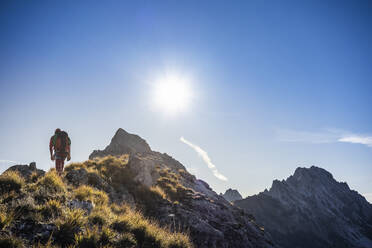 Männlicher Bergsteiger beim Wandern am Bergkamm an einem sonnigen Tag - MCVF00913