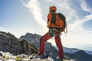 Männlicher Alpinist mit Rucksack auf einem Berg stehend - MCVF00920