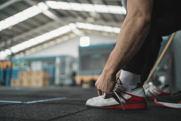 Male athlete tying shoelace in gym - SNF01516