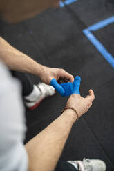 Male athlete wrapping thumb with weight lifting tape - SNF01520