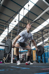 Junger männlicher Sportler, der Gewichte hebt, während er im Fitnessstudio trainiert - SNF01523