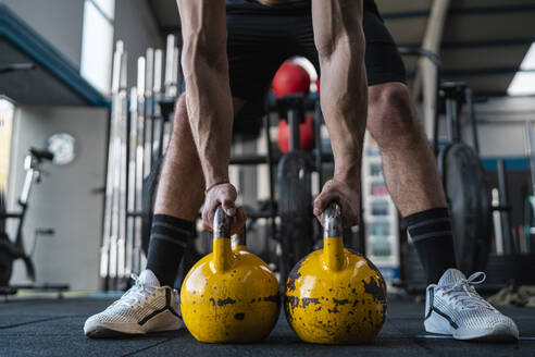 Muskulöser männlicher Athlet, der Kettlebells im Fitnessstudio hält - SNF01560