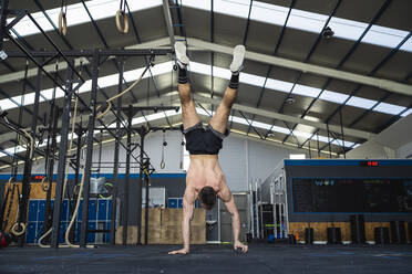 Junger männlicher Sportler macht Handstand im Fitnessstudio - SNF01562