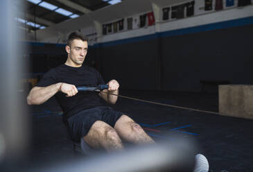 Young male athlete practicing on rowing machine in gym - SNF01565