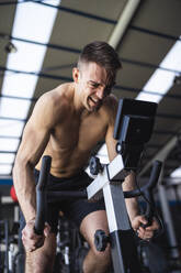 Determined sportsman on exercise bike while working out in gym - SNF01569