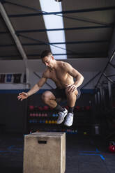 Sportler, der beim Training im Fitnessstudio auf einen Holzkasten springt - SNF01572