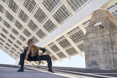 Woman with blond hair crouching on road - RDGF00350