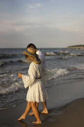 Girlfriend walking with boyfriend at beach on sunset - SSGF00086