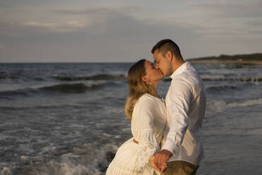 Young couple kissing on mouth at beach by sea - SSGF00090